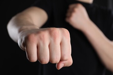 Obraz premium Man showing fist with space for tattoo on black background, selective focus