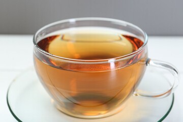 Glass cup of tea on white table, closeup
