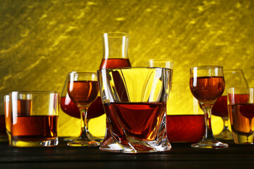 Different delicious liqueurs in glasses on dark wooden table