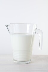 Jug of fresh milk on wooden table