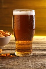 Glass of beer and pretzel crackers on wooden table