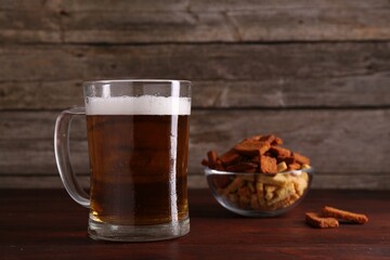 Glass mug of beer and rusks on wooden table