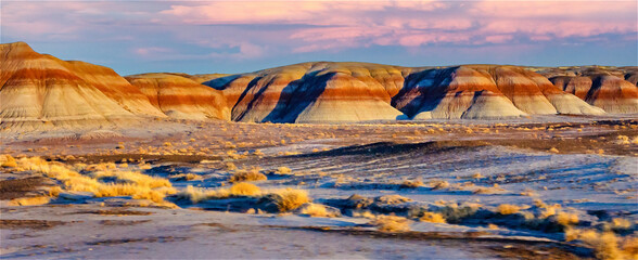 The vibrant hues of sunset illuminate the undulating hills of the painted desert