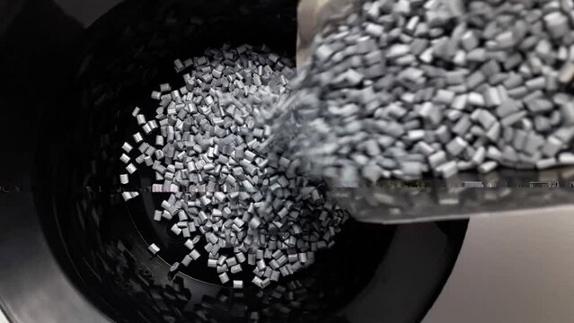 Pearl silver masterbatch granules are poured into a black measuring cup.Color pigment carrier polymers in the plastic industry