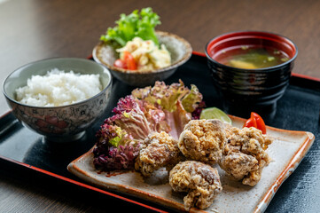 A plate of fried chicken with rice, salad, and miso soup.