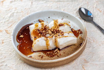 A photo of a plate of four pieces of mochi with brown sugar syrup and crushed peanuts.