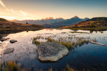 Landscape of sunrise shines over Lac Guichard with Arves massif and lake reflection in autumn at French Alps, France