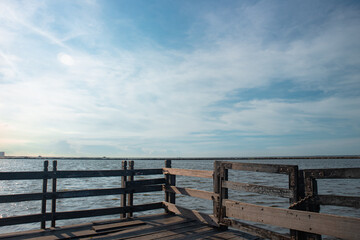 Obraz premium Scenic view of a tranquil waterfront pier under a bright blue sky, capturing the serene beauty of the sea and the peaceful ambiance of a calm day by the water.