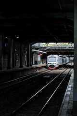 Obraz premium shows a commuter line train passing through the platform hallway of BNI city station, which is quite dark during the day. The train is white with red accents, and the platform is empty
