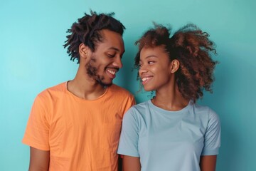Obraz premium Portrait of a satisfied afro-american couple in their 30s wearing a simple cotton shirt isolated on pastel blue background