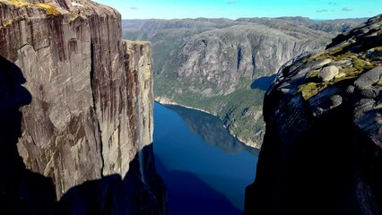 A couple of men and women at the Kjeragbolten Majestic hanging stone, Kjerag, Norway, Lysefjordbrau in Norwegian fjord Lysefjord, Forsand municipality of Rogaland county, Norway