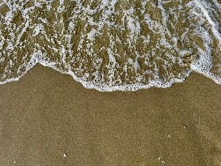 Photo of waves on the sand seen from above. Background ideas