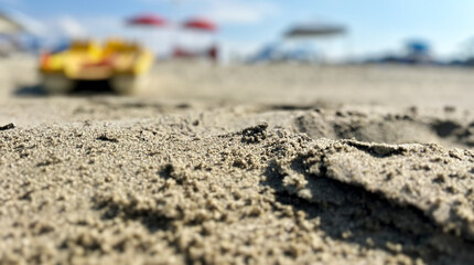 Closeup photograph of the sand of a beach with umbrellas