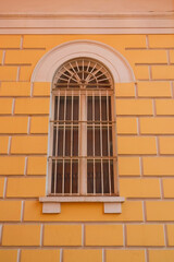 yellow building with a window. The window is adorned with a metal grate, which adds a unique and interesting design element to the building