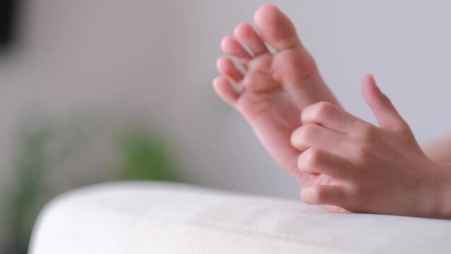 boy scratching his legs, feet while lying on the sofa in a bright room