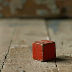 a tiny old wooden toy cube painted red, lost and abandoned on a dusty floor