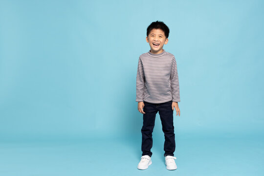 Happy Asian little boy smiling and standing isolated on light blue background, Full body composition and six years old