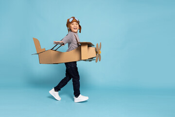 Asian little boy aviator playing and running with cardboard airplane isolated on blue sky background, Kid toy diy concept © comzeal
