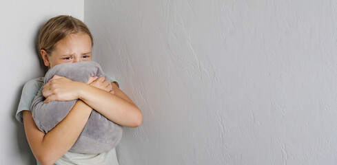 Tired little kid girl crying standing on white domestic wall at home