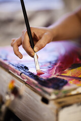 Hand using brush on an artistic painting. Female artist creating art.