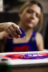 Female artist making an artistic painting. Pouring paint from a bottle with her hand.