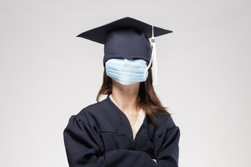 Graduation girl wearing gown and cap. Female student wearing protective mask all over her face.
