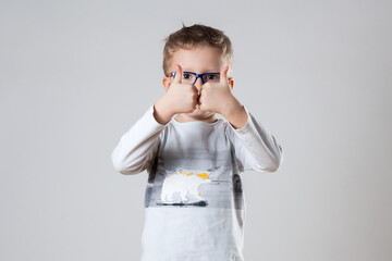 A young boy, wearing glasses, enthusiastically gives a thumbs up gesture