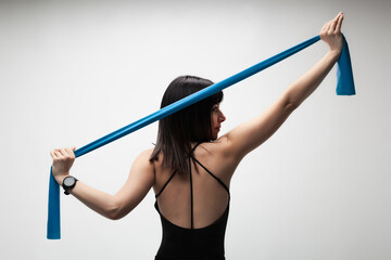 Young woman exercising with resistance band in a studio setting, focusing on fitness and health