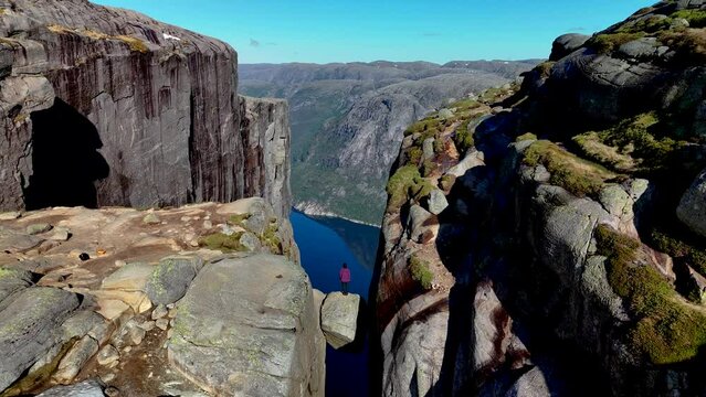 Asian women stand on the rock of Kjeragbolten Fjord, Norway, Lysefjordbrau in Norwegian fjord Lysefjord, Forsand municipality of Rogaland county, Norway
