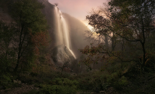 View among the vegetation of the La Mea waterfall in Puentedey, Burgos on a mysterious autumn morning shrouded in fog