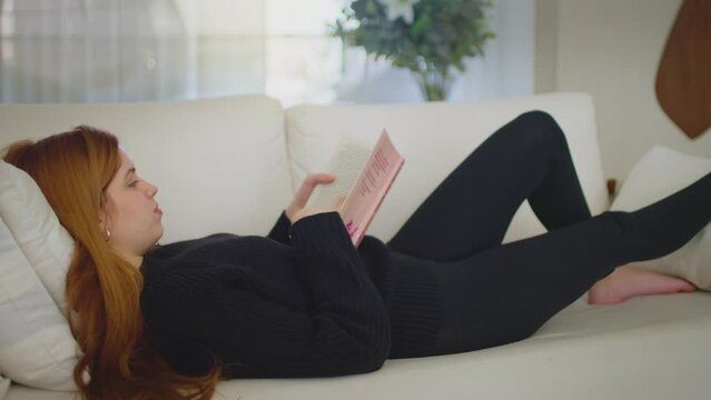 Young woman finishing a book reading the last page. Charming girl happy to have finished a book. Reading romance. Video concept of dreaming out loud. 