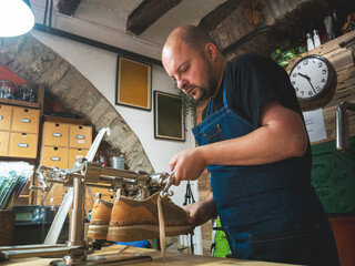 Shoemaker working with lasts repairing shoes. Trades, business.