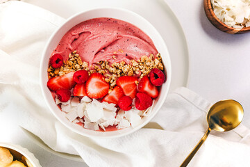 Delicious strawberry smoothie bowl topped with berries, granola and coconut chips, overhead view