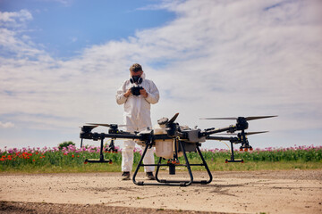 A male operator holding and using a controller, starting an agro drone, wearing a protective uniform and a mask.