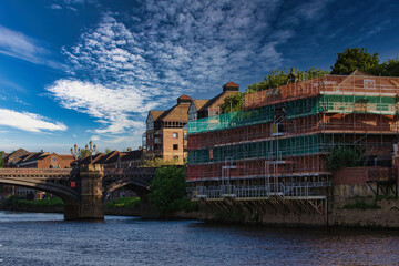 Fototapeta premium Riverside construction and bridge under a partly cloudy sky in York, North Yorkshire