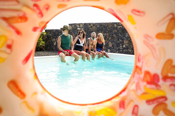 Friends relaxing by the pool framed by an inflatable ring