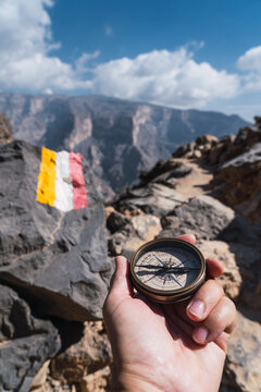 Anonymous person exploring Oman's mountainous landscape with a compass