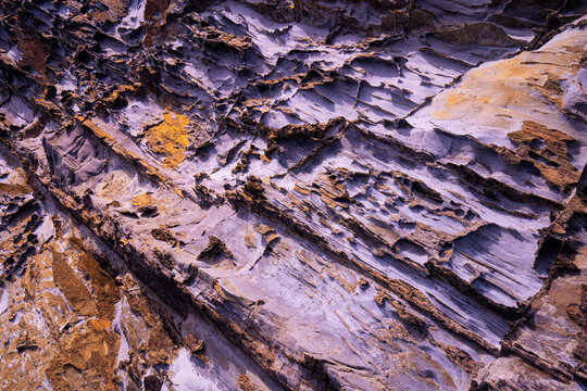 Textured rock layers with yellow mineral deposits