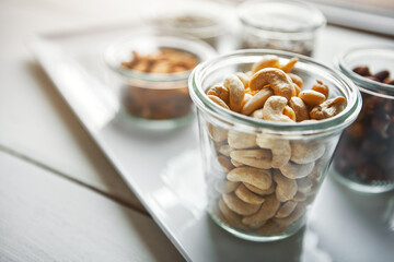Bowls, nuts and cashew on plate, kitchen or breakfast for nutrition, health or table with diet for wellness. Hazelnut, almond and storage in glass container for meal prep, food and morning at house
