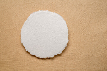 circular sheet of blank white watercolor paper against handmade amate bark paper