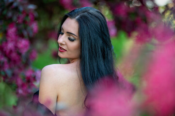 Naklejka premium Woman with dark hair in a garden. Background with selective focus and copy space