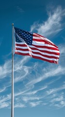 Naklejka premium USA flag on a flagpole against a blue sky