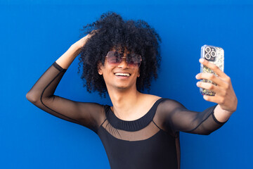 Non-Binary Confidence: Smiling Selfie with Sunglasses, Afro Hair, and Blue Background