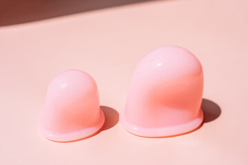 Pink silicone vacuum cups for anti-cellulite massage on a pink background.