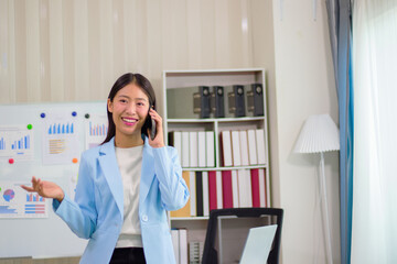 Beautiful Asian business woman uses digital tablet and laptop to do remote work at the office, online seminar or video call.