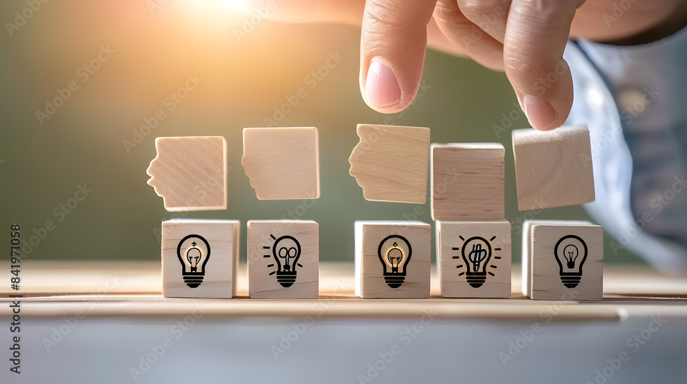 Poster a hand placing wooden blocks with icons of heads and lightbulbs on them in a row. symbolizing the id