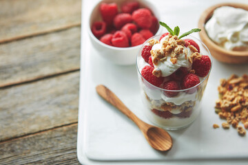 Cereal, container and yogurt with fruit on plate for healthy food, nutrition and sneak at breakfast. Top view, raspberry and dairy in glass with protein for organic, morning meal and vegan diet
