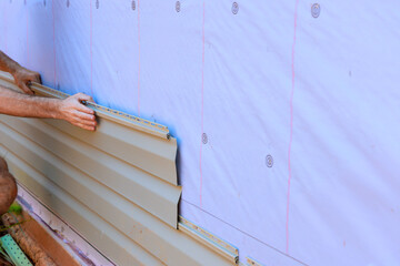 An installation process for vinyl PVC siding on new home facade by handyman