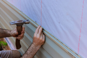 Handyman installs vinyl PVC siding on new home facade during construction