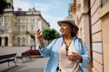 Happy female tourist making video call on smart phone on  street.